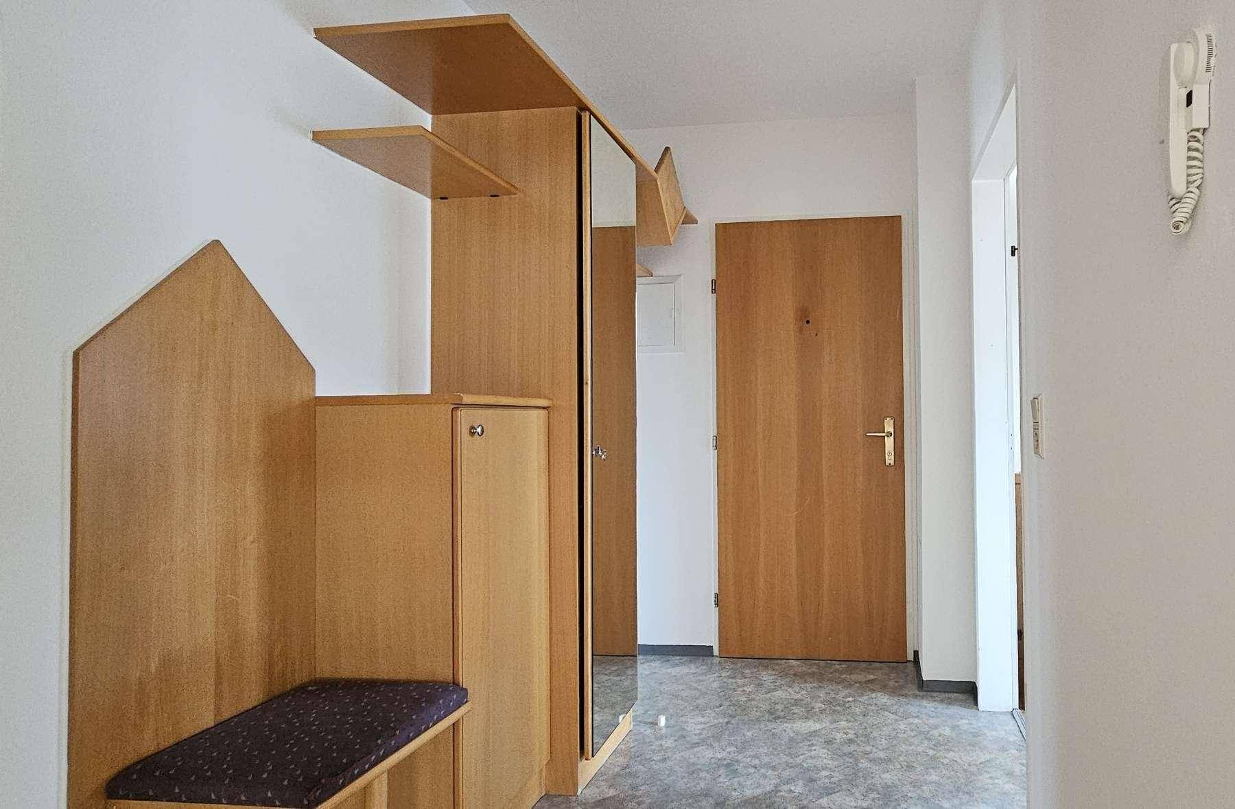 Eingangsbereich mit praktischer Garderobe, Spiegel und Holztür, ausgestattet mit Fliesenboden.