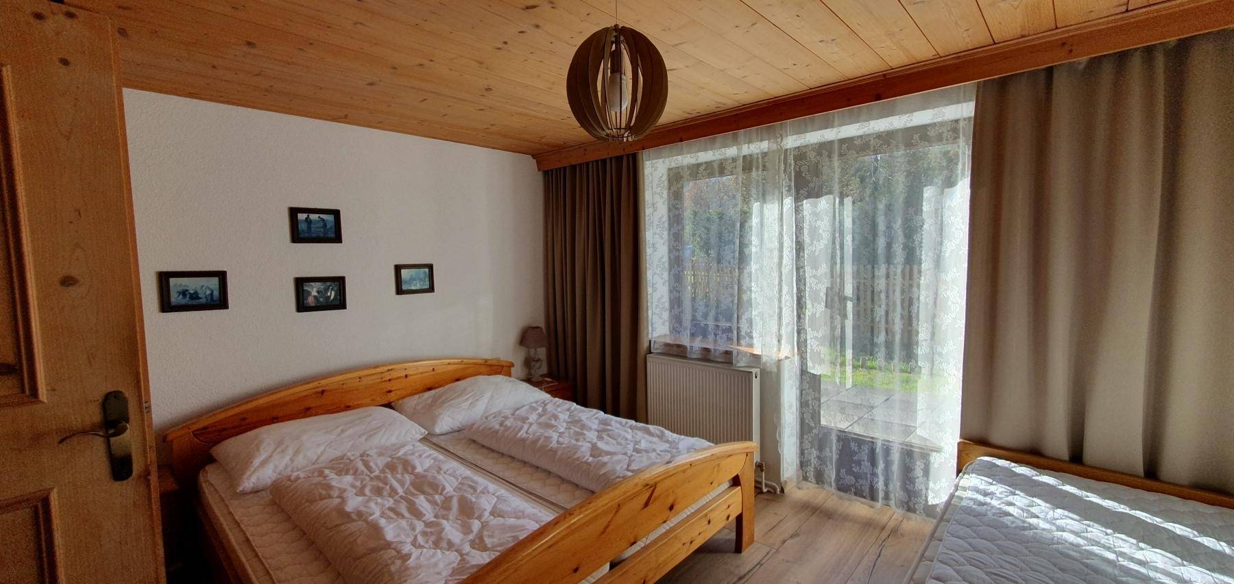 Helles Schlafzimmer mit Holzbetten, Holzboden und Zugang zum Balkon.