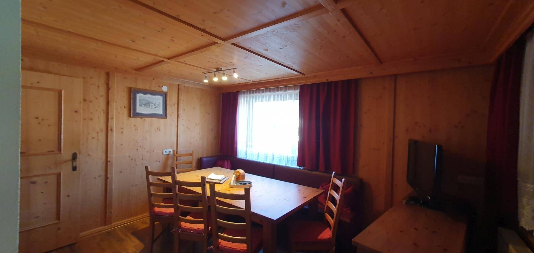 Gemütlicher Essbereich mit langem Holztisch und traditioneller Holztäfelung.