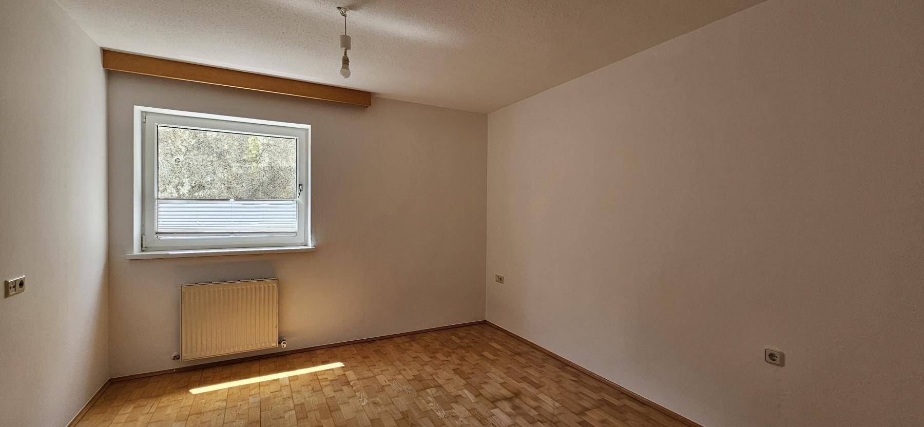 Ruhiges Zimmer mit Parkettboden und einem Fenster, das natürliches Licht spendet, ideal als Schlafzimmer.