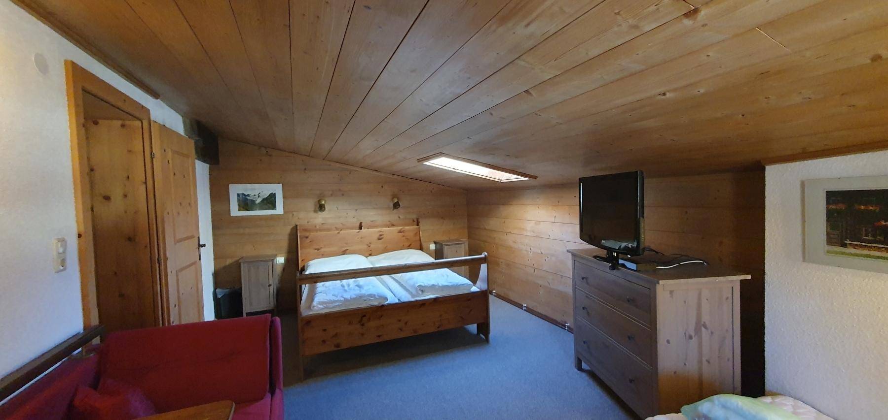 Gemütliches Schlafzimmer im Dachgeschoss mit Holztäfelung und Dachschräge.
