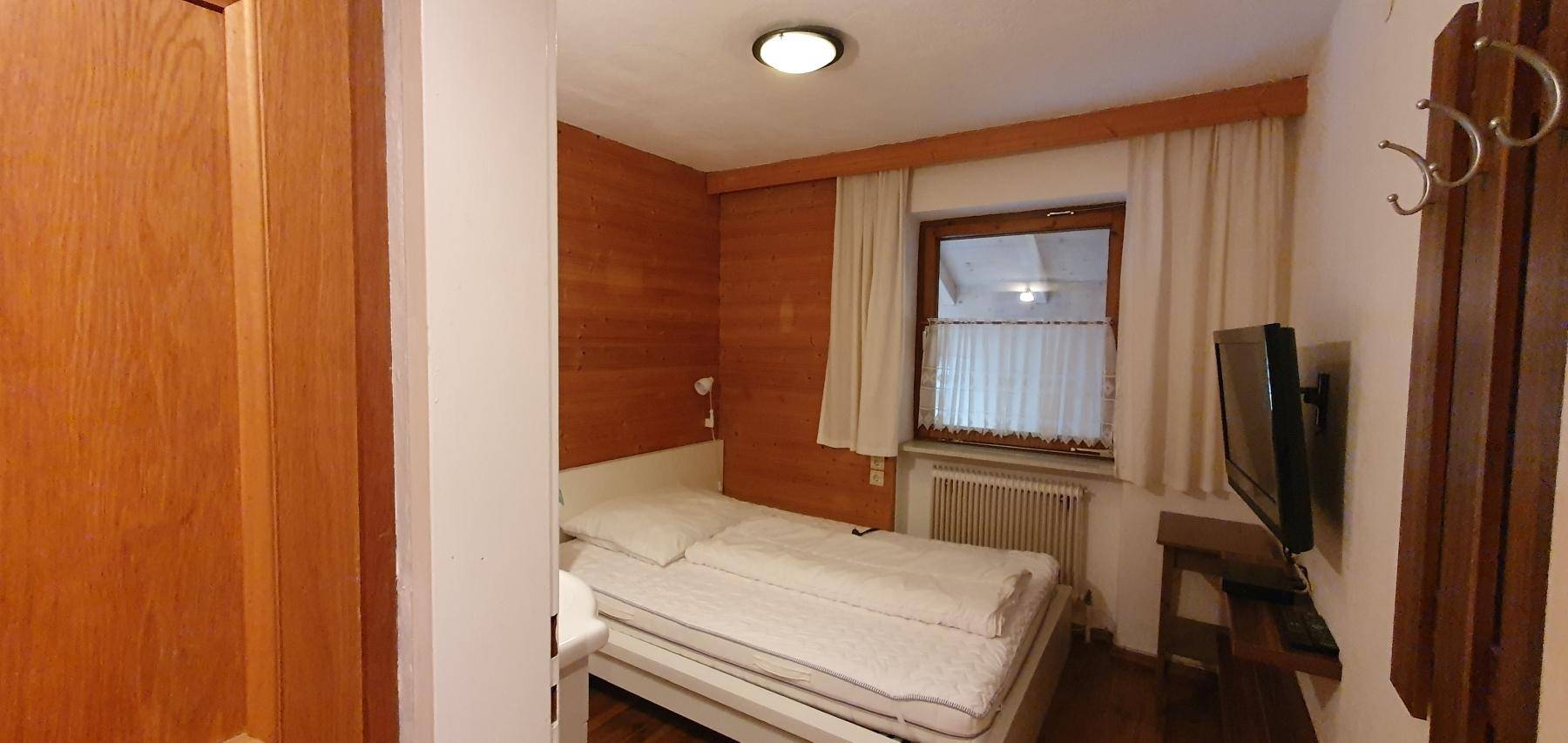 Kleines Schlafzimmer mit Einzelbett und Holzwand.