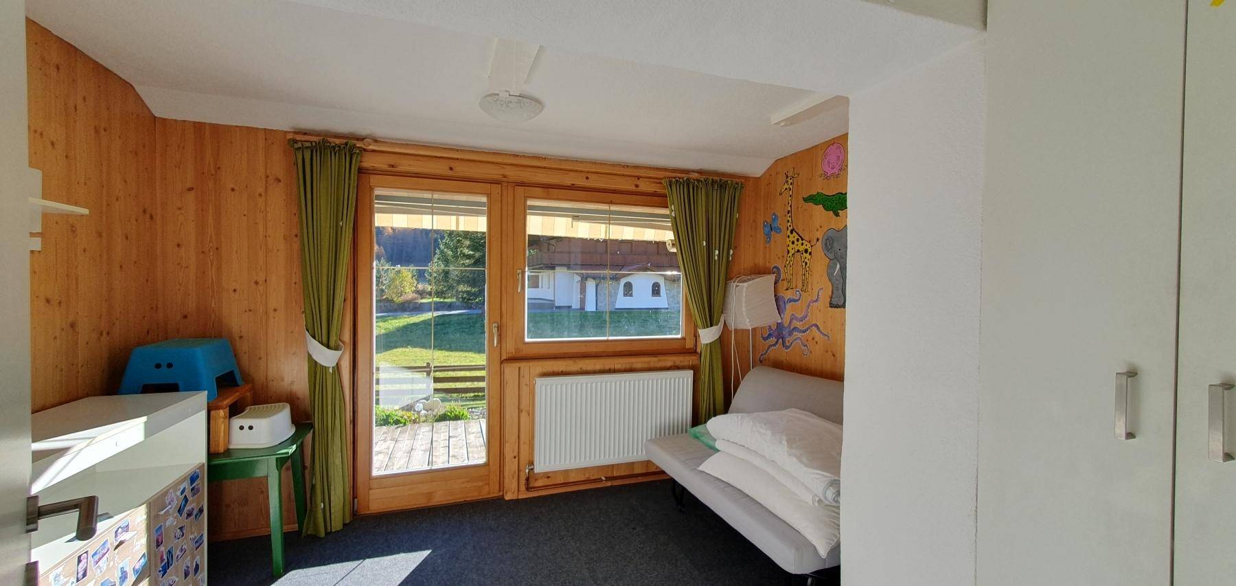 Kinderfreundliches Schlafzimmer mit Holztäfelung und Zugang zum Außenbereich.