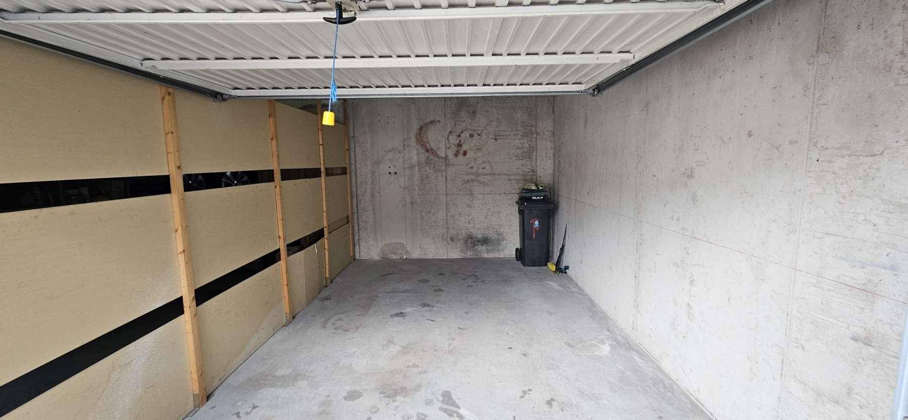 Geräumige Garage mit Betonboden und -wänden, bietet viel Platz für ein Fahrzeug und Lagerung.