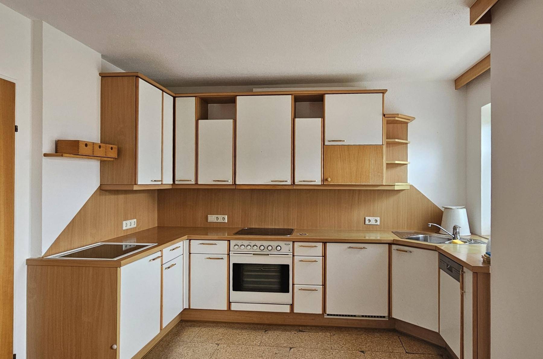 Funktionale Küche mit Holzschränken, weißen Fronten und integrierten Geräten, bereit zur Nutzung.