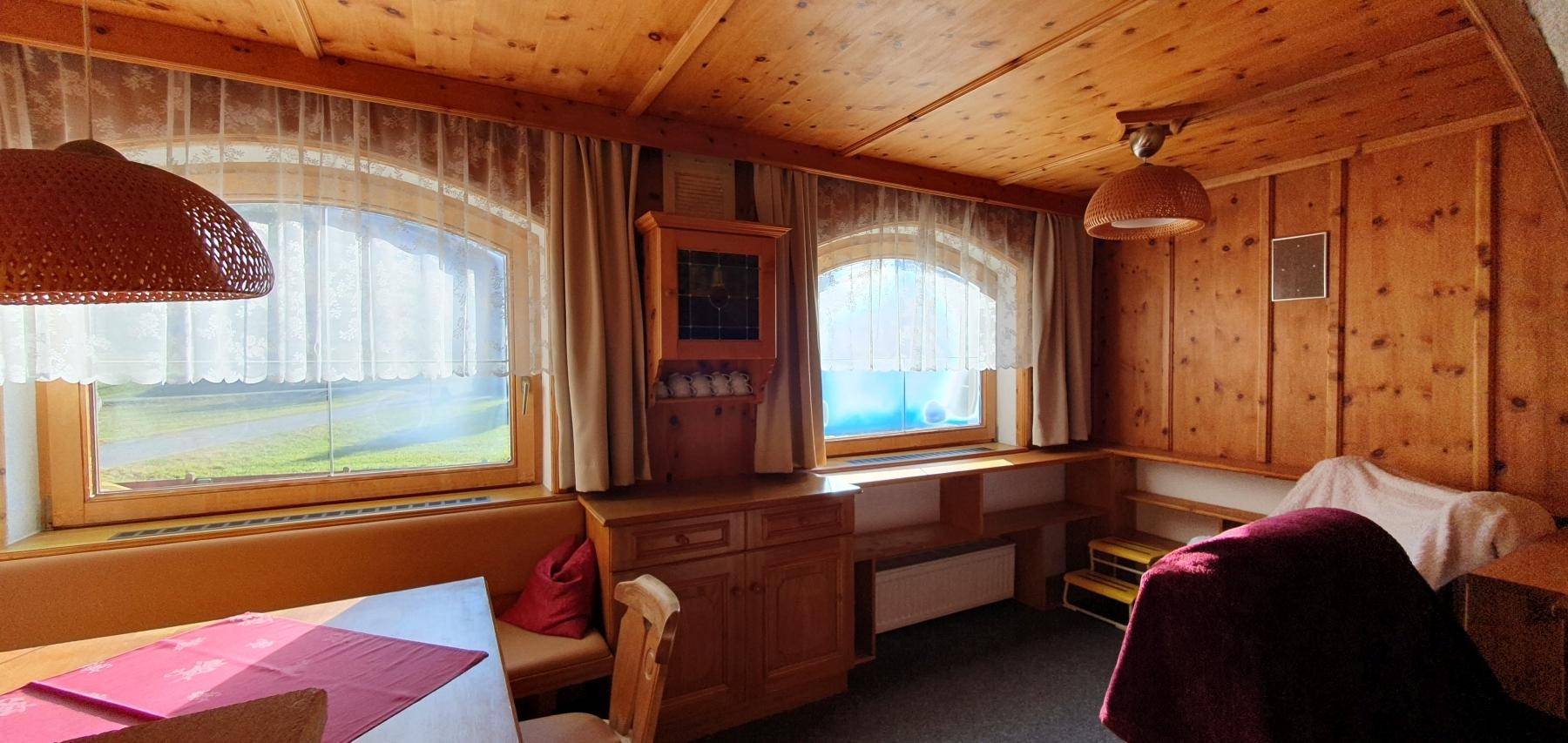 Rustikaler Essbereich mit Holztäfelung und großen Fenstern, die viel Licht hereinlassen.