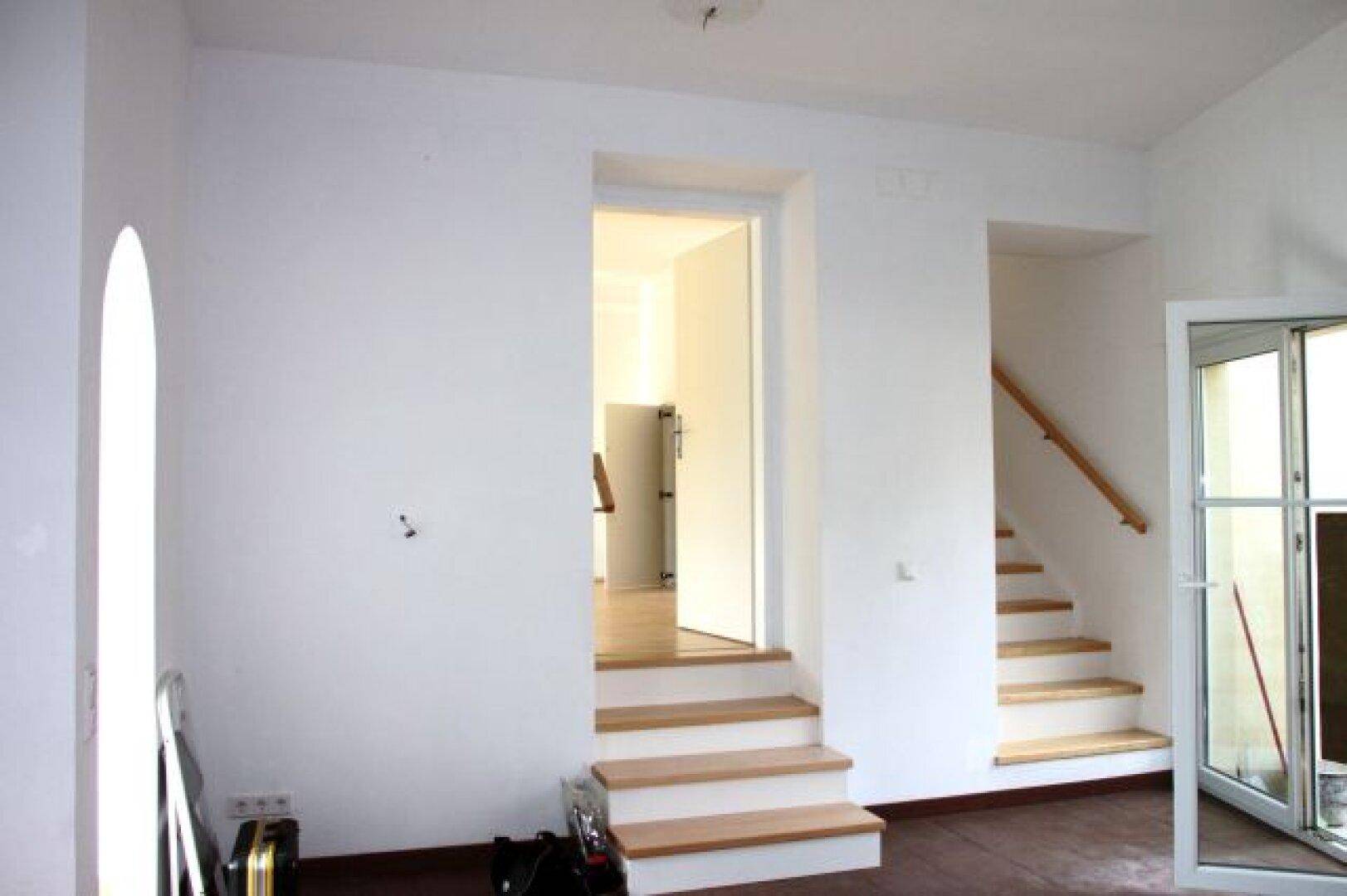 Heller Flurbereich mit Holztreppen, die zu verschiedenen Ebenen führen.