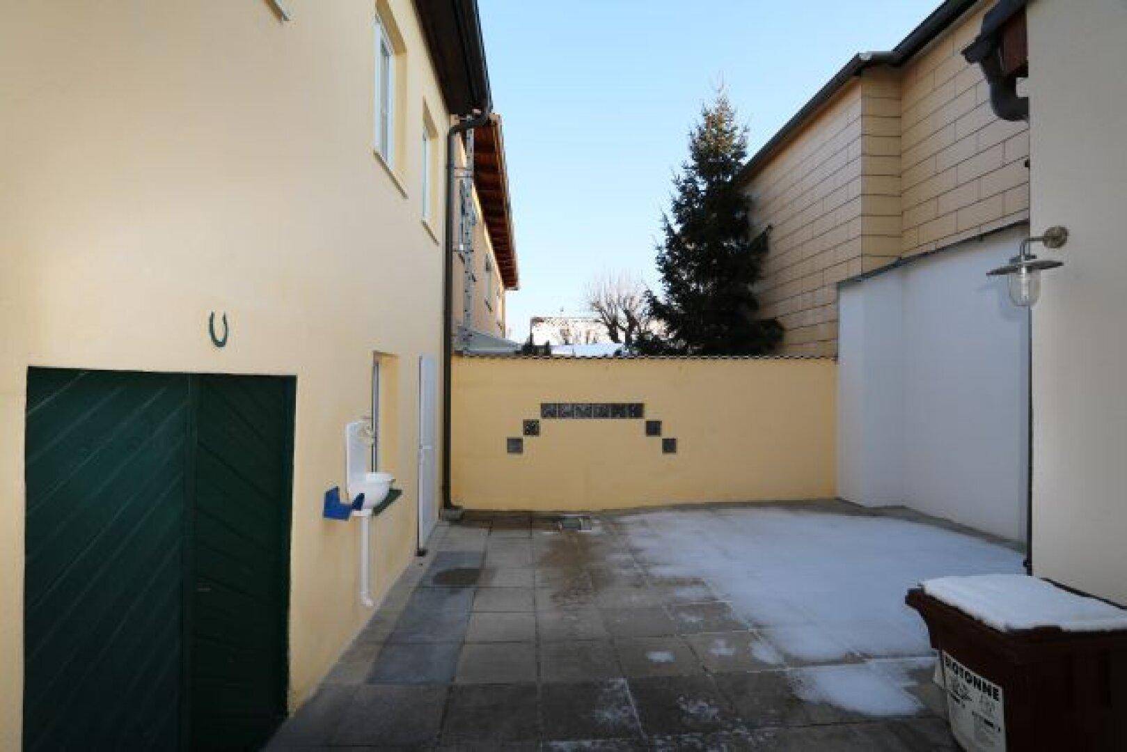 Gepflasterter Innenhof zwischen Gebäuden mit Spuren von Schnee.