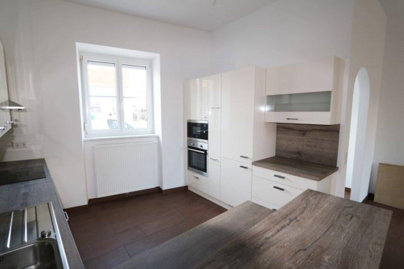 Küchenzeile mit integriertem Backofen, Mikrowelle und Fenster für Tageslicht.