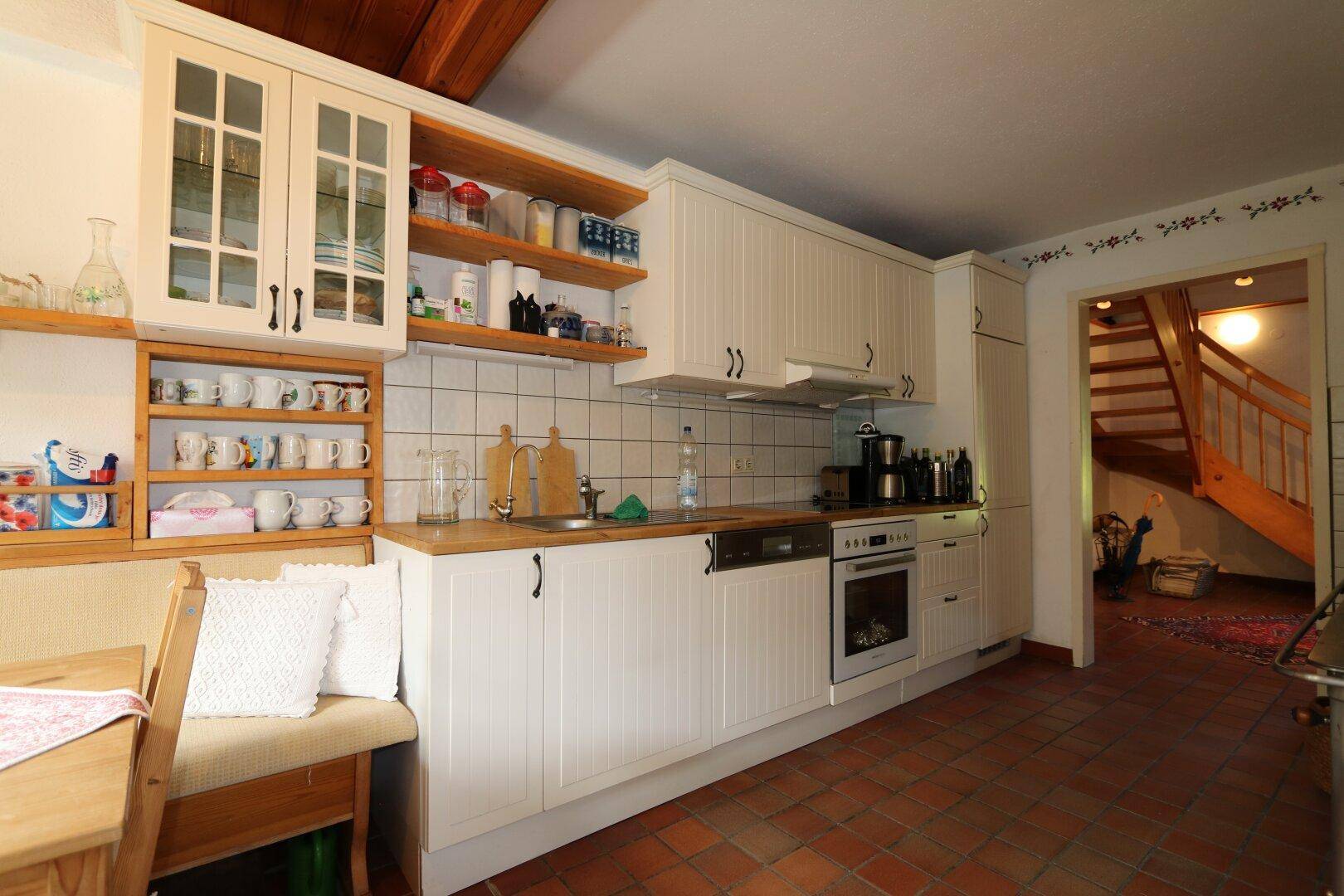 möblierte Küche mit kleiner Eckbank und Holzküchenofen