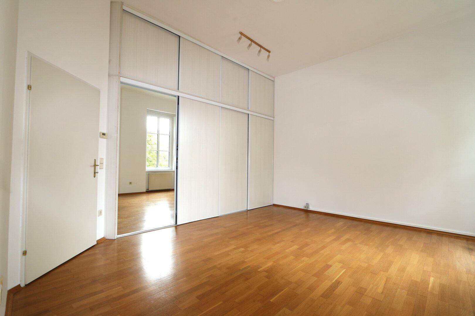Schlafzimmer mit Parkettboden und integriertem Spiegelschrank, der den Raum optisch vergrößert.