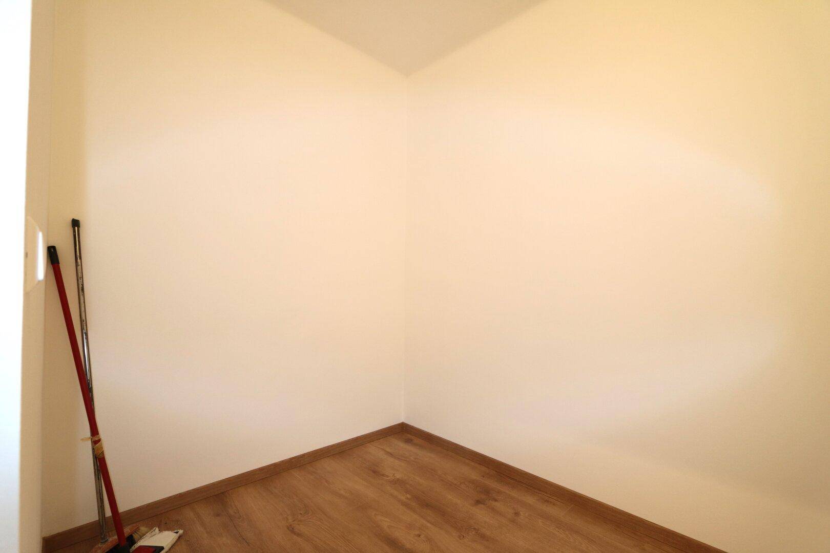 Kleiner Abstellraum mit Laminatboden und hellen Wänden, ideal für Haushaltsgeräte.