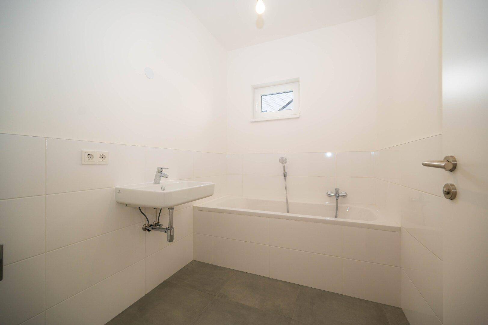 Bad mit Wanne, Waschmaschinenanschluss und Fenster