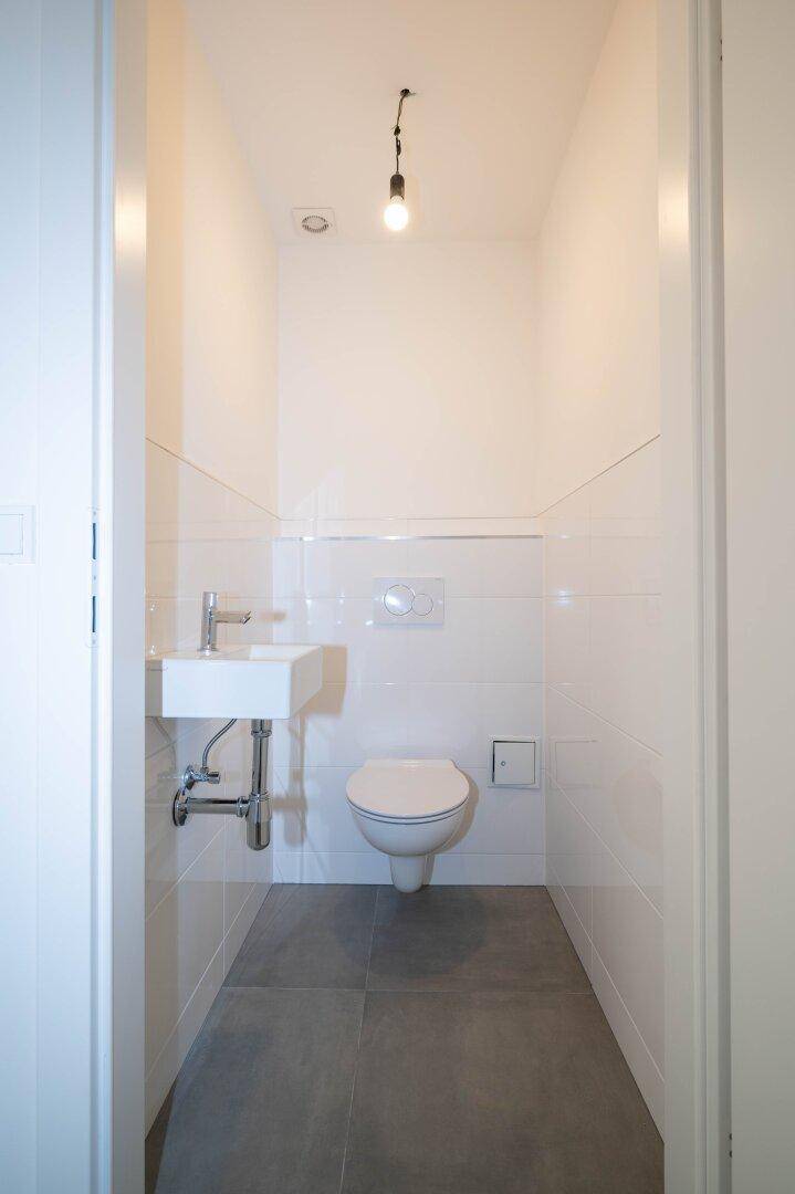Kleines Gäste-WC mit wandhängender Toilette und einem kompakten Waschbecken.