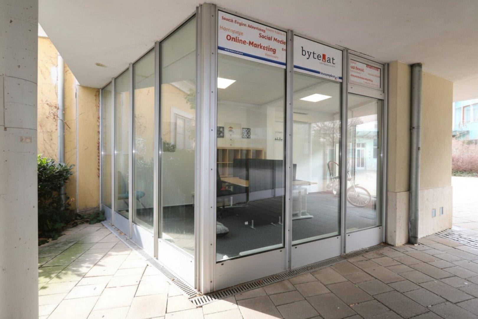 Moderne Glasfassade eines Bürogebäudes mit Blick auf den Innenhof, viel Licht im Inneren.