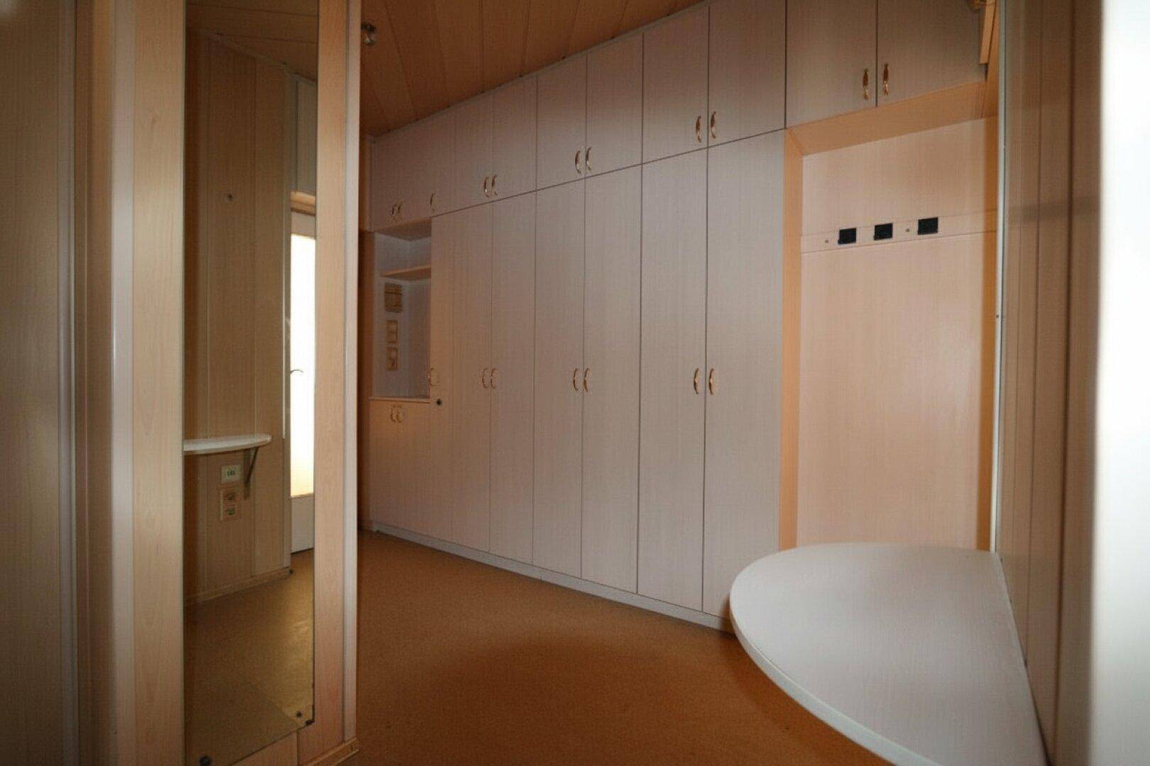 Flur mit vielen Einbauschränken und Holzverkleidung, bietet praktischen Stauraum.