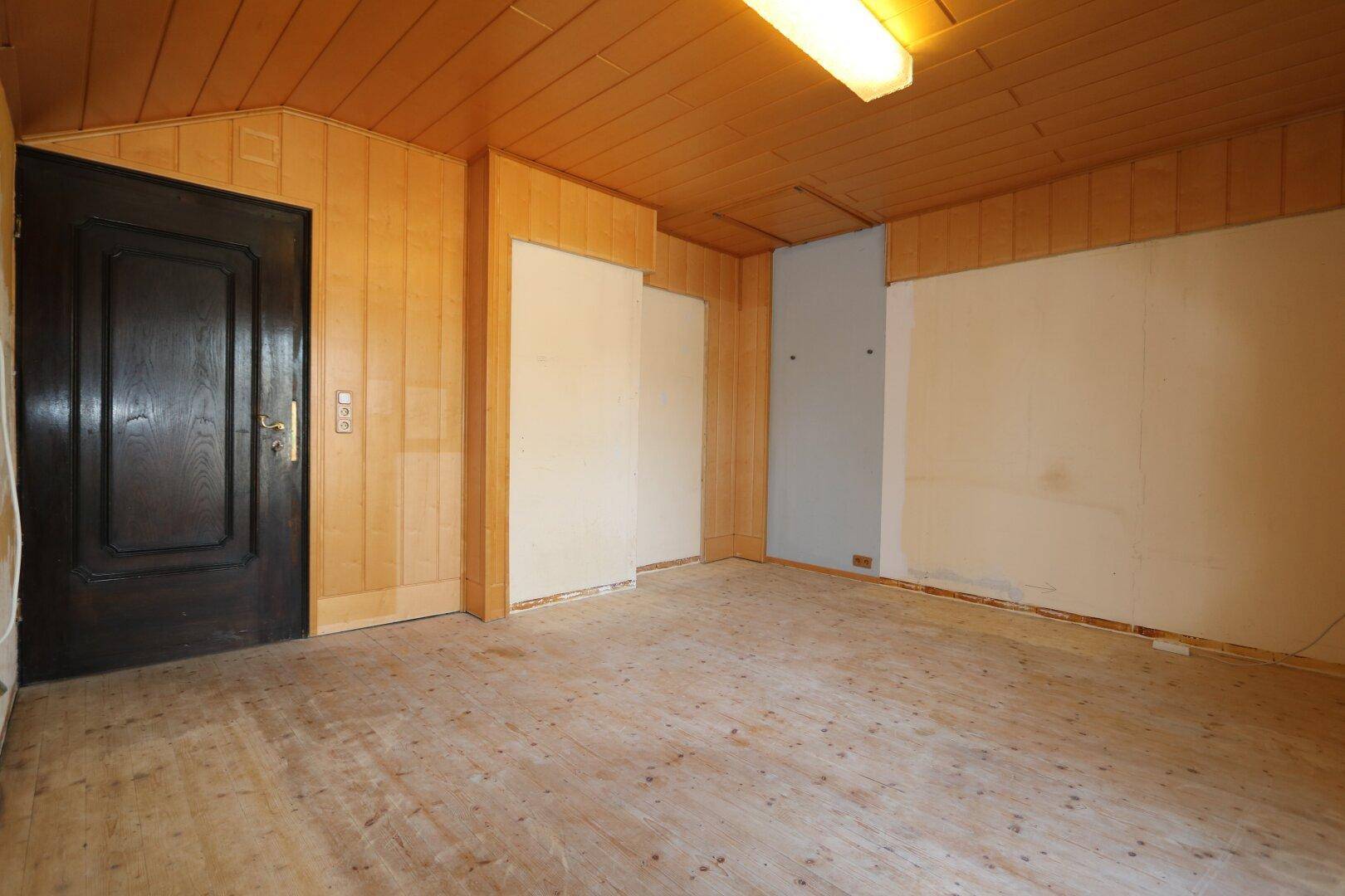 Raum mit Holzboden und Holzverkleidung, ideal für ein Schlafzimmer oder Büro.