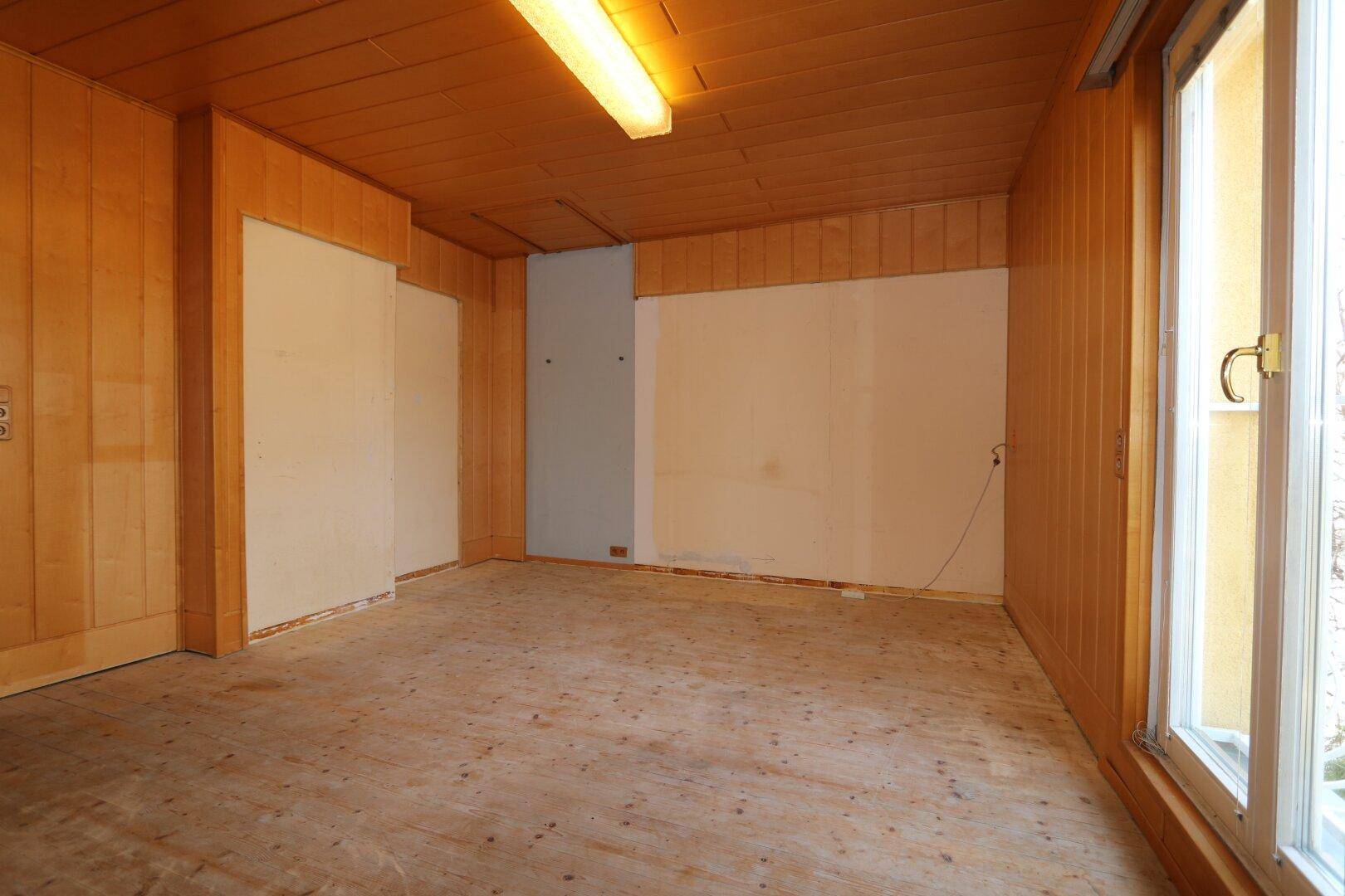 Raum mit Holzboden und Holzverkleidung, bietet viel natürliches Licht.