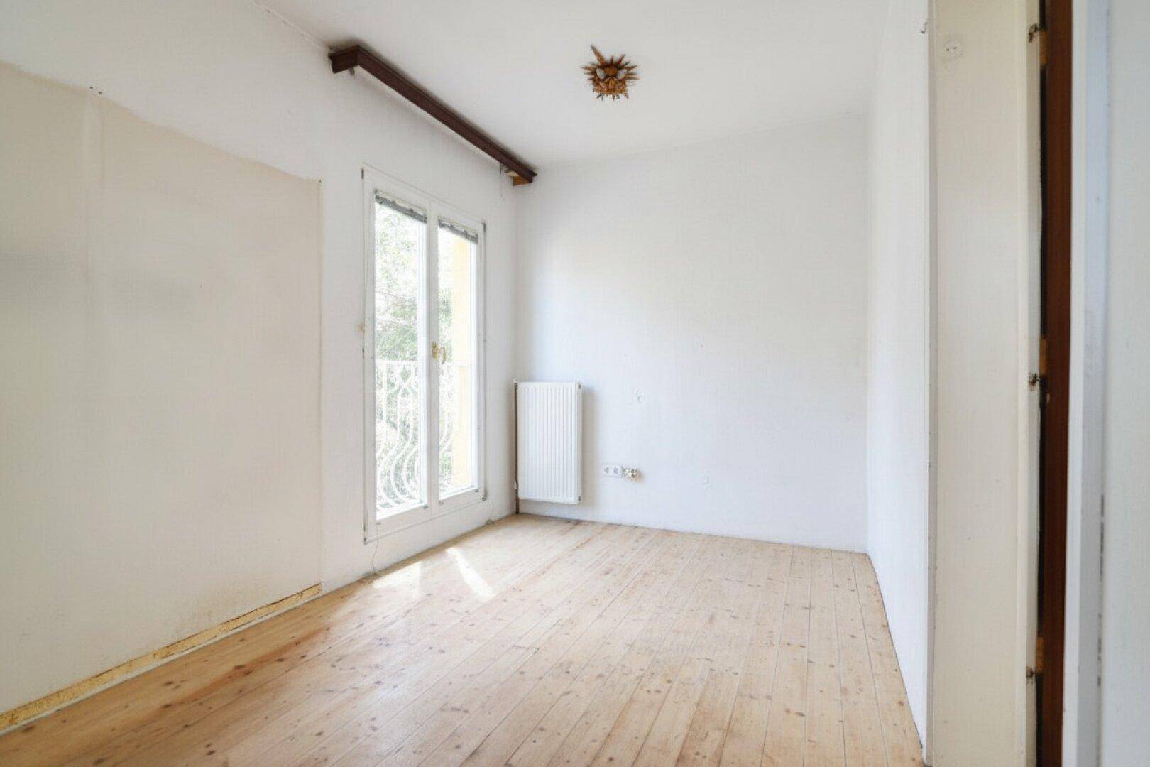 Heller Raum mit Holzboden und Zugang zu einem französischen Balkon.