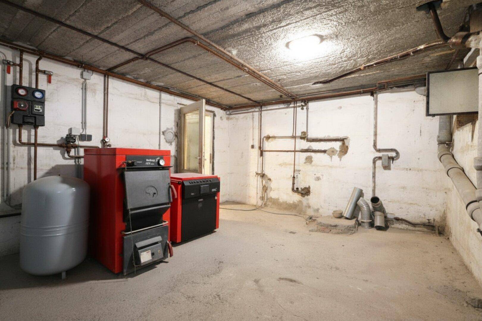 Heizungsraum im Keller mit Ölheizung und Warmwasserspeicher.