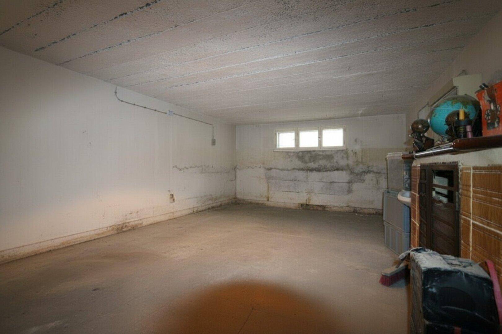 Leerer Kellerraum mit Fenster und viel Platz für Lagerung.
