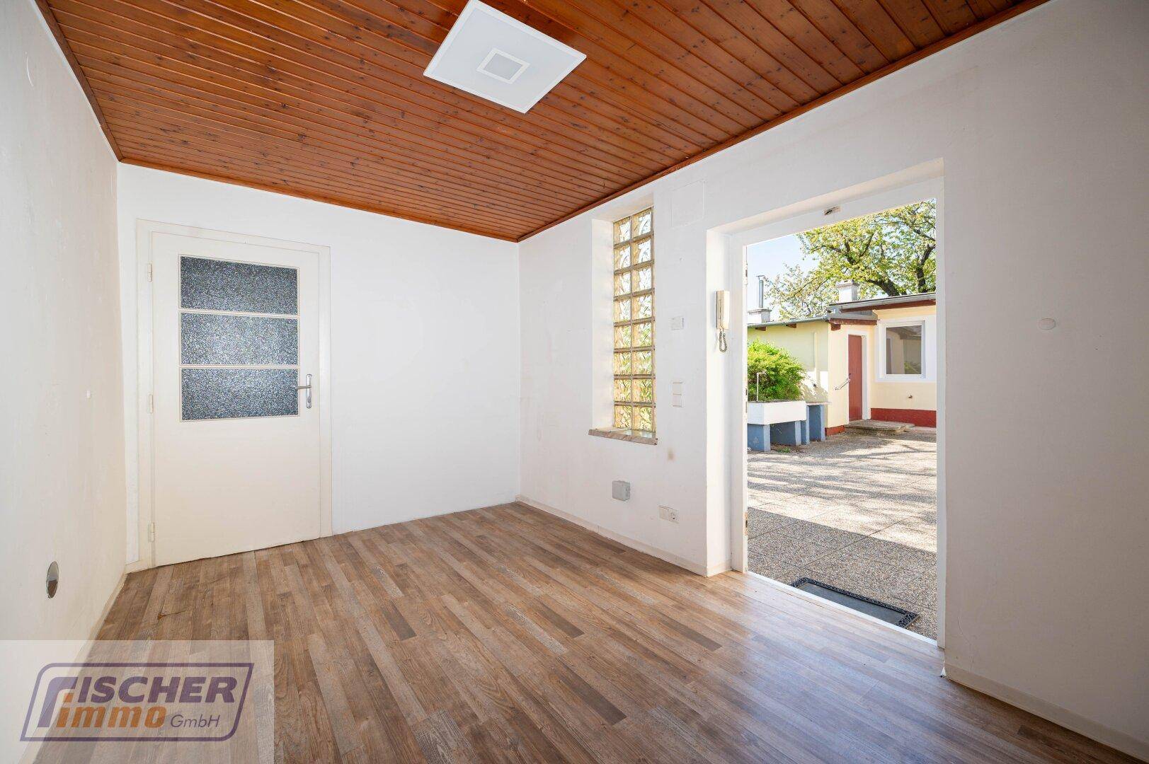 Raum mit Holzbalkendecke, Laminatboden und direktem Zugang zum Außenbereich.