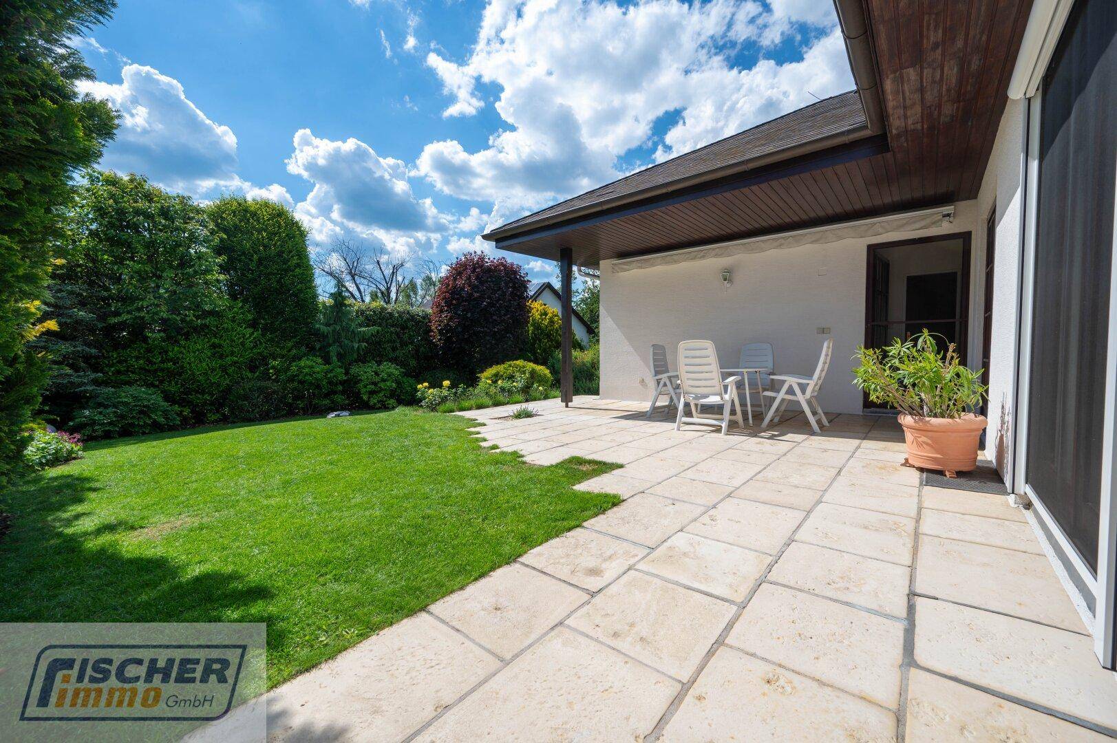 Große, sonnige Terrasse mit Gartenmöbeln und direktem Zugang zum weitläufigen, gepflegten Rasen.