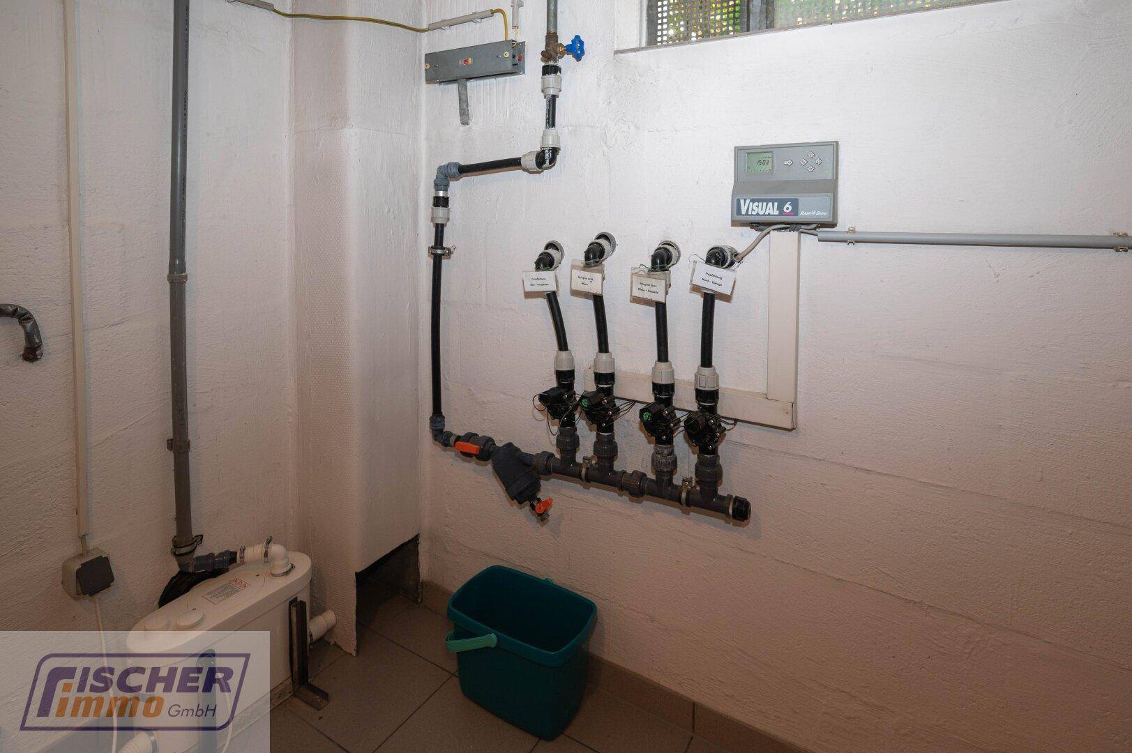 Technikraum im Keller mit Wasserleitungen und Steuerungseinheit.