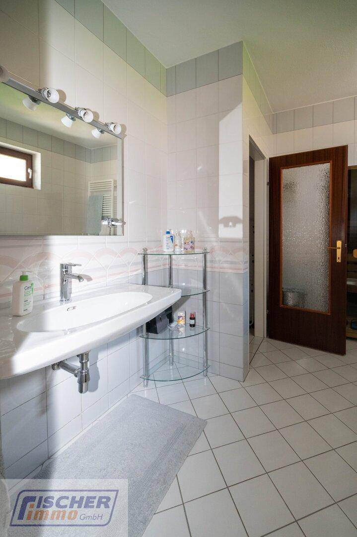 Helles Badezimmer mit Waschbecken, großem Spiegel und weißen Fliesen.