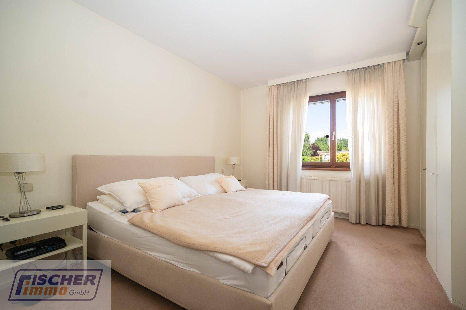 Gemütliches Schlafzimmer mit Doppelbett, Teppichboden und Fenster mit Blick ins Grüne.