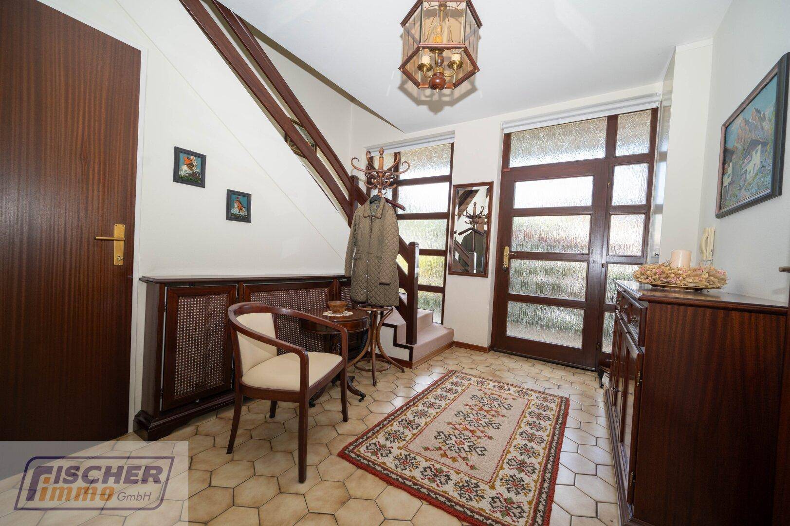 Eingangsbereich mit Fliesenboden, Garderobe und Treppe zum Obergeschoss.