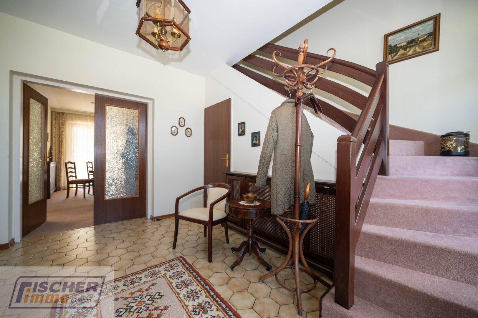 Heller Flur mit Treppe, Fliesenboden und Zugang zu weiteren Räumen.