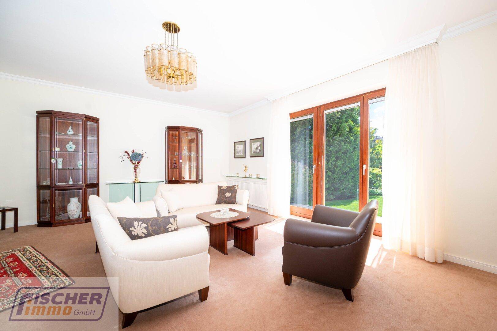 Wohnzimmer mit beigem Teppichboden, eleganten Vitrinen und direktem Zugang zum Außenbereich.