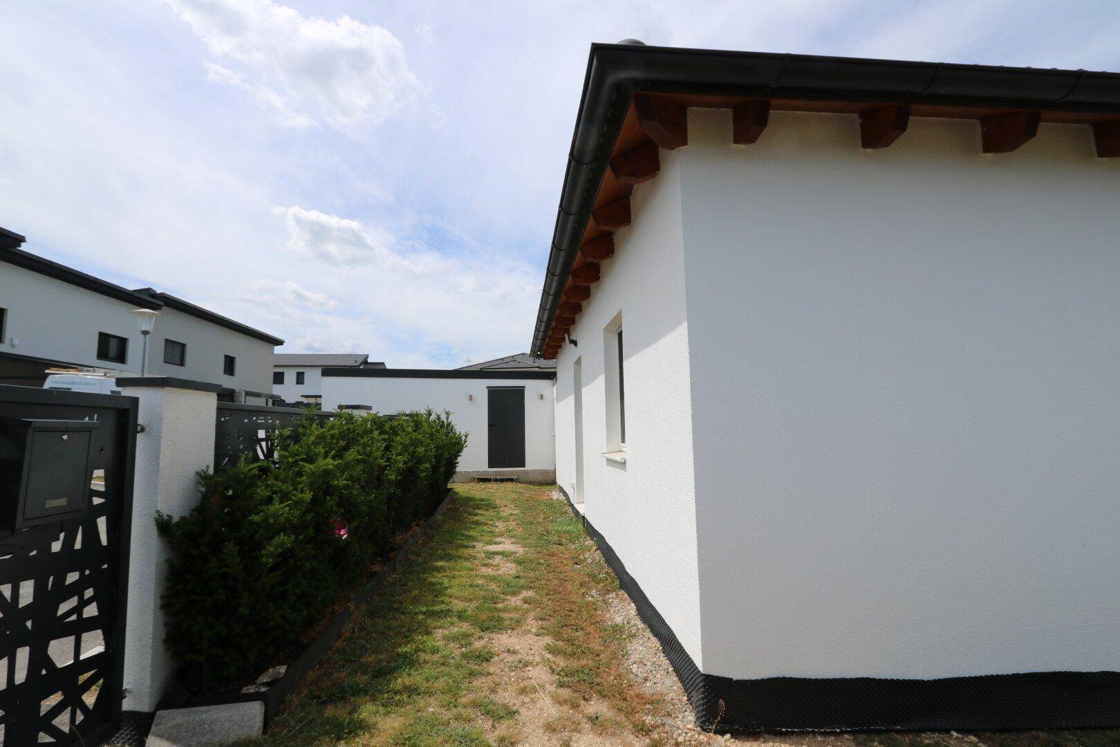 Seitenansicht des Hauses mit schmalem Weg und Hecke.