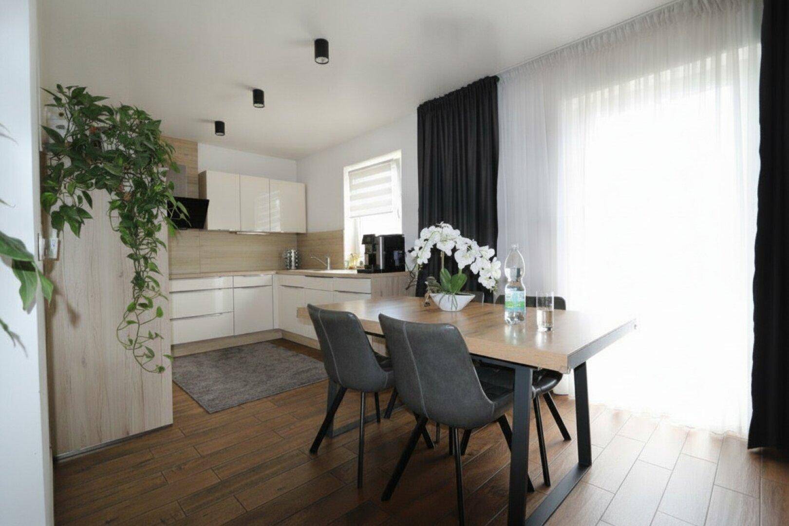 Essbereich mit Holztisch und Stühlen, angrenzend an die moderne Küche.