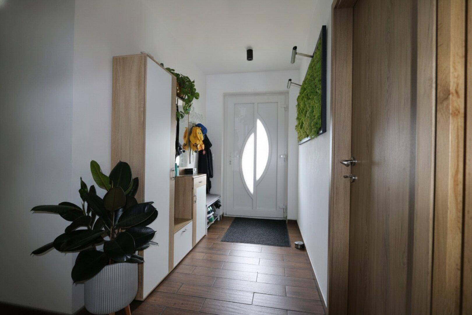 Heller Eingangsbereich mit Garderobe, Schuhschrank und moderner Haustür.