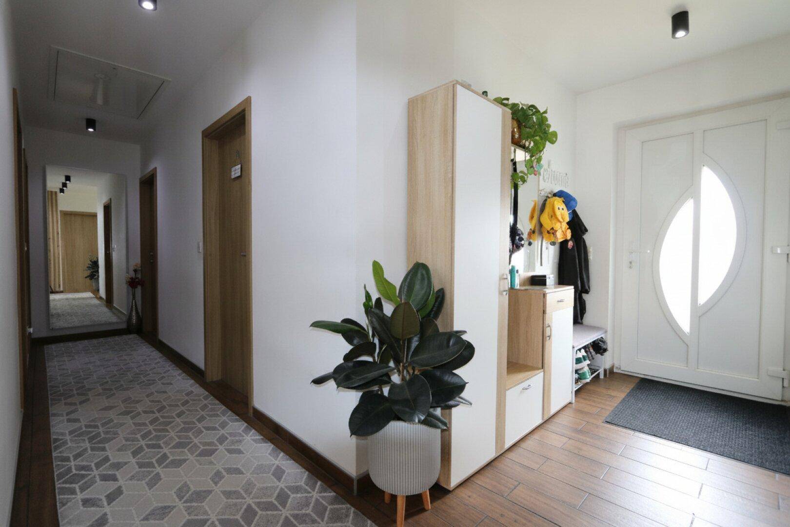 Langer Flur mit Holzboden, Garderobe und Zugang zu weiteren Räumen.