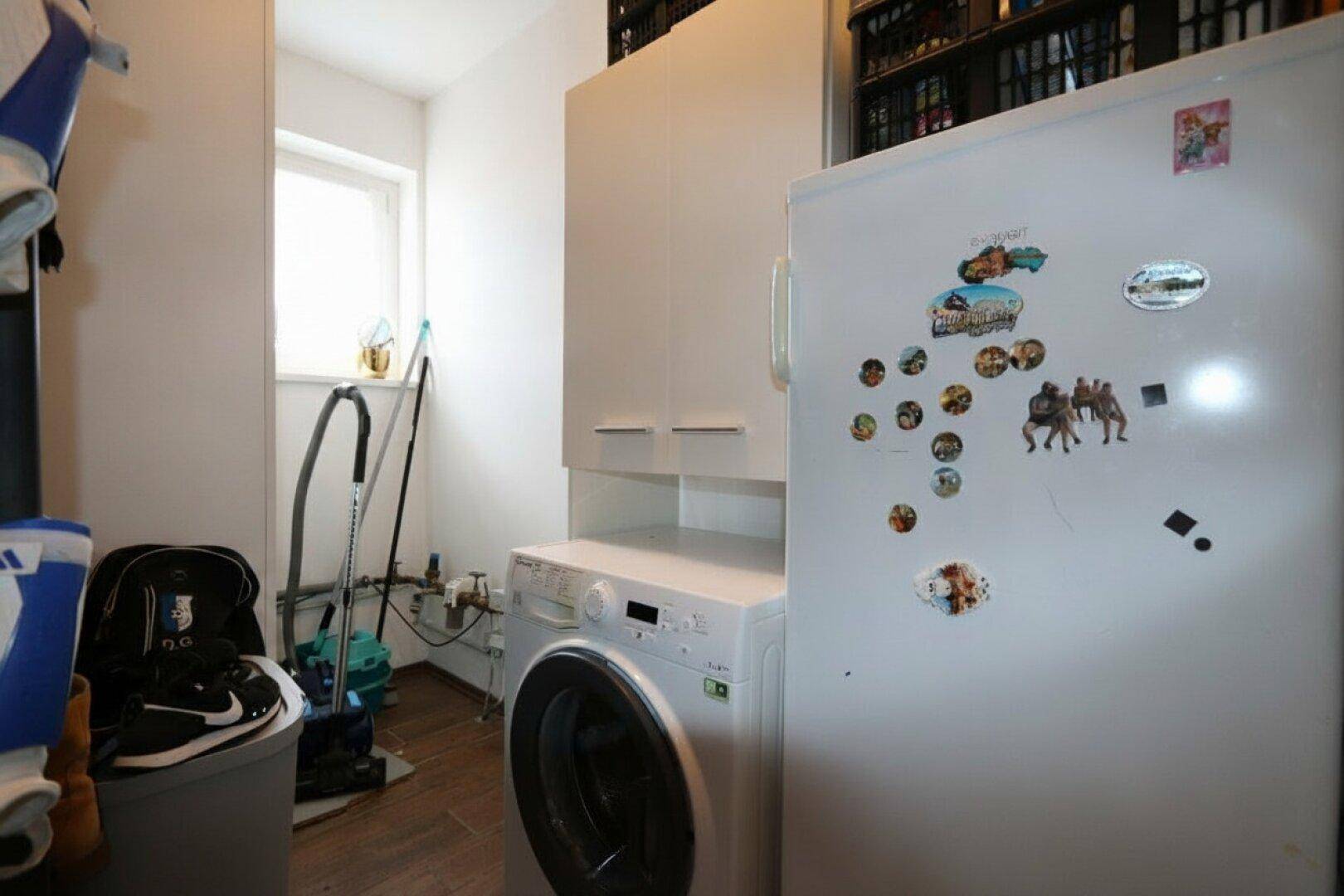 Hauswirtschaftsraum mit Waschmaschine, Kühlschrank und Fenster.