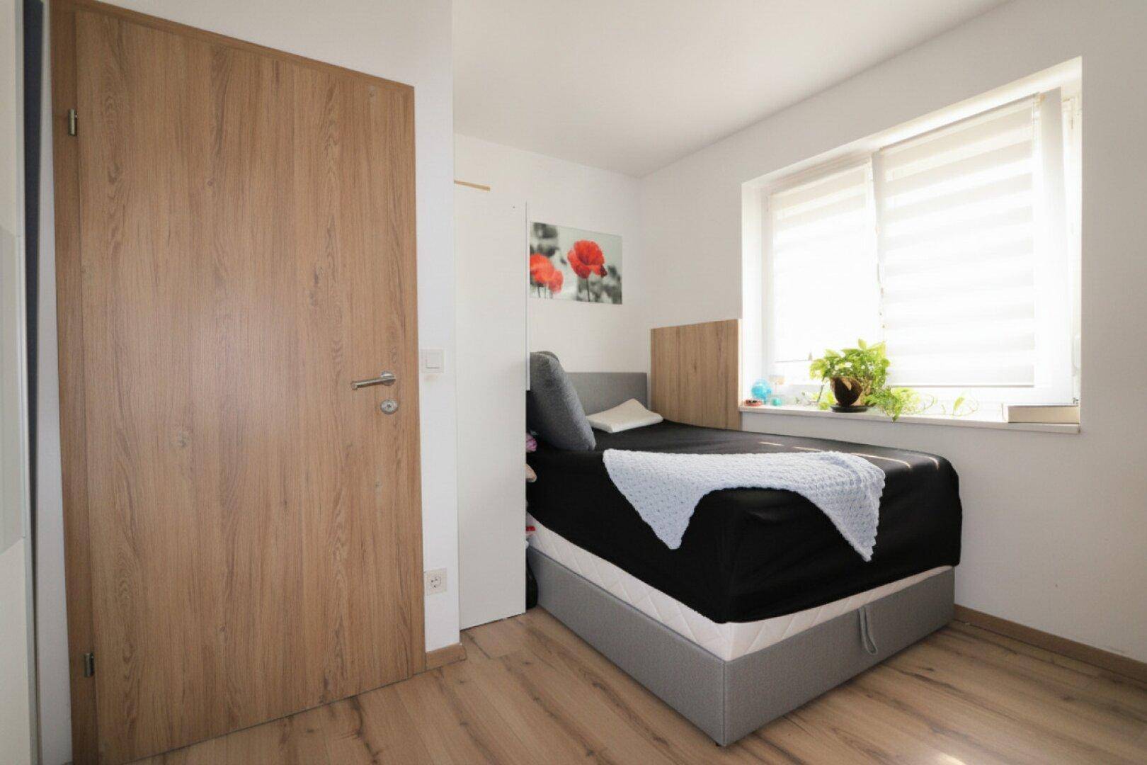 Schlafzimmer mit Einzelbett, Holzboden und Fenster.