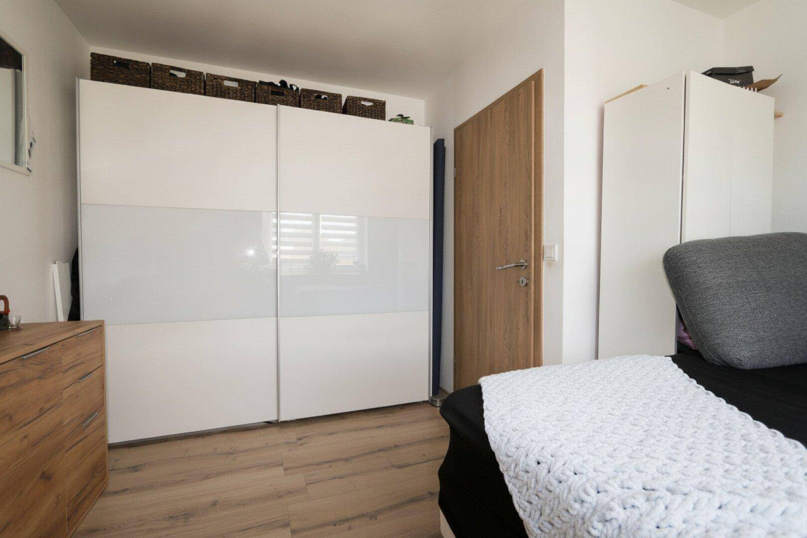 Schlafzimmer mit großem Kleiderschrank, Holzboden und Fenster.