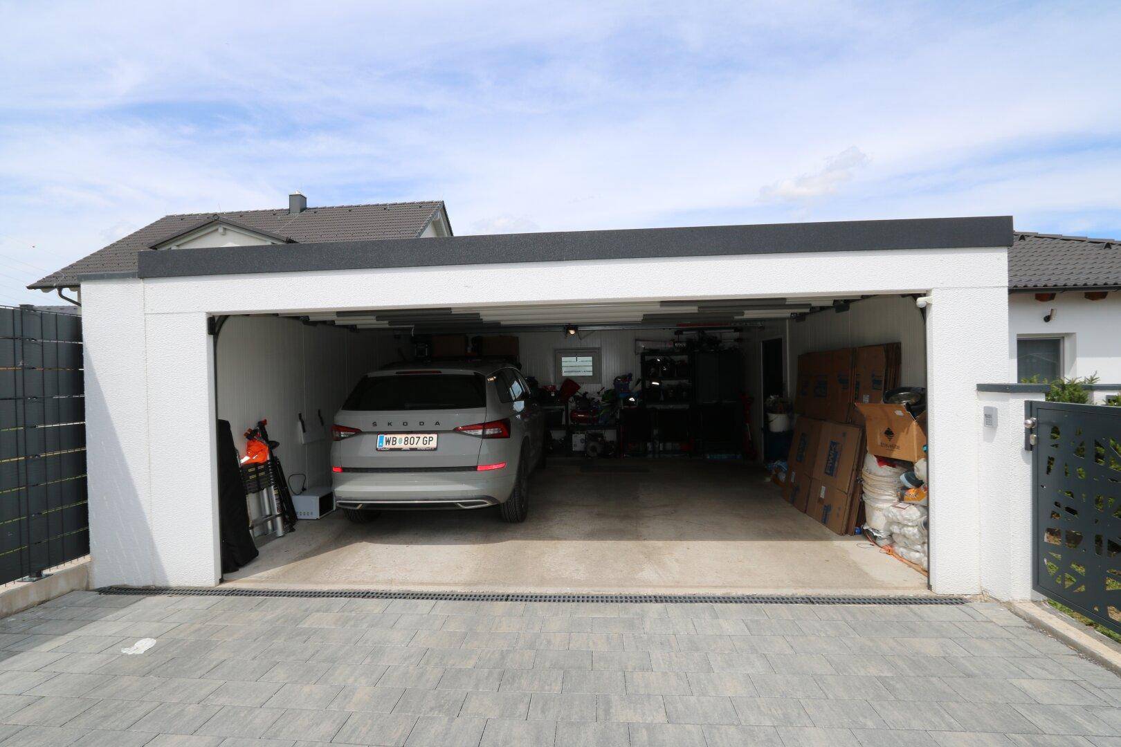 Geräumige Doppelgarage mit einem geparkten Auto und Stauraum.