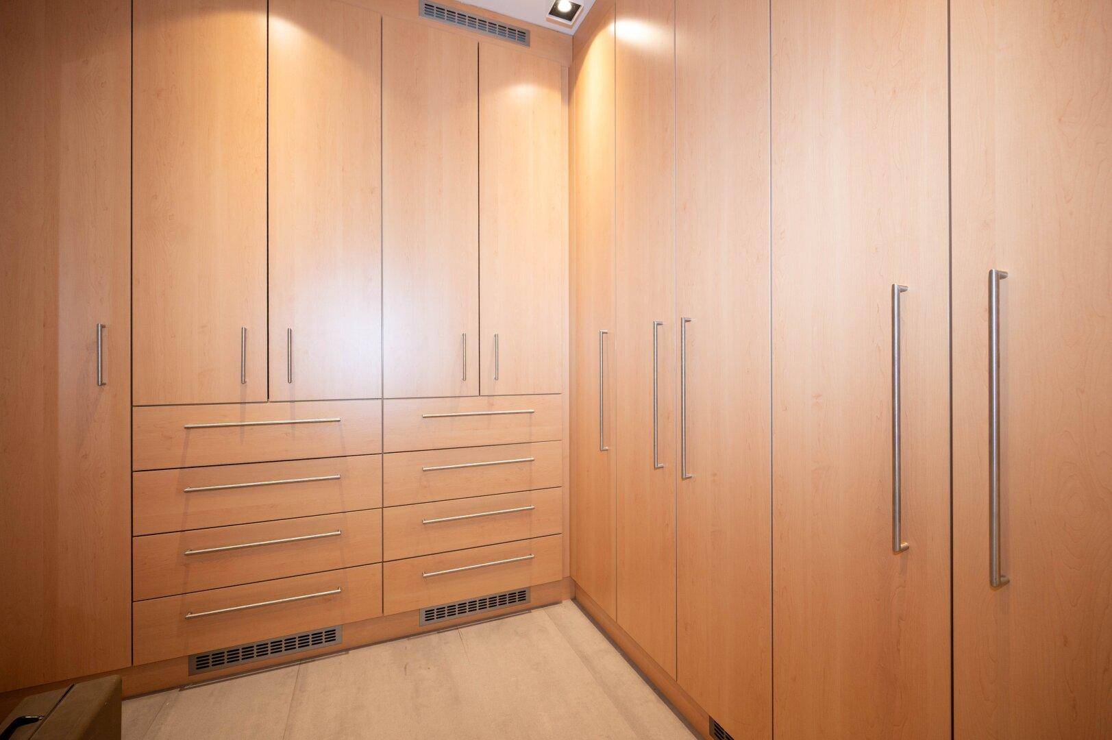 Praktischer begehbarer Kleiderschrank mit maßgefertigten Holzschränken und Schubladen.