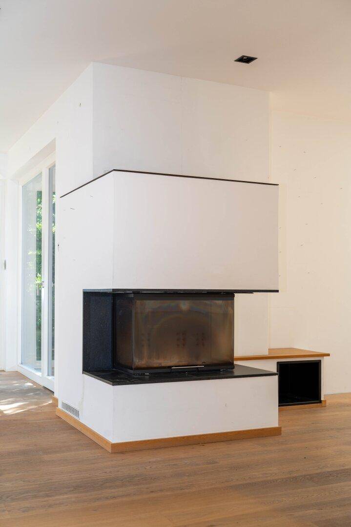 Moderner Kamin als zentrales Element im Wohnbereich, umgeben von hellen Wänden.