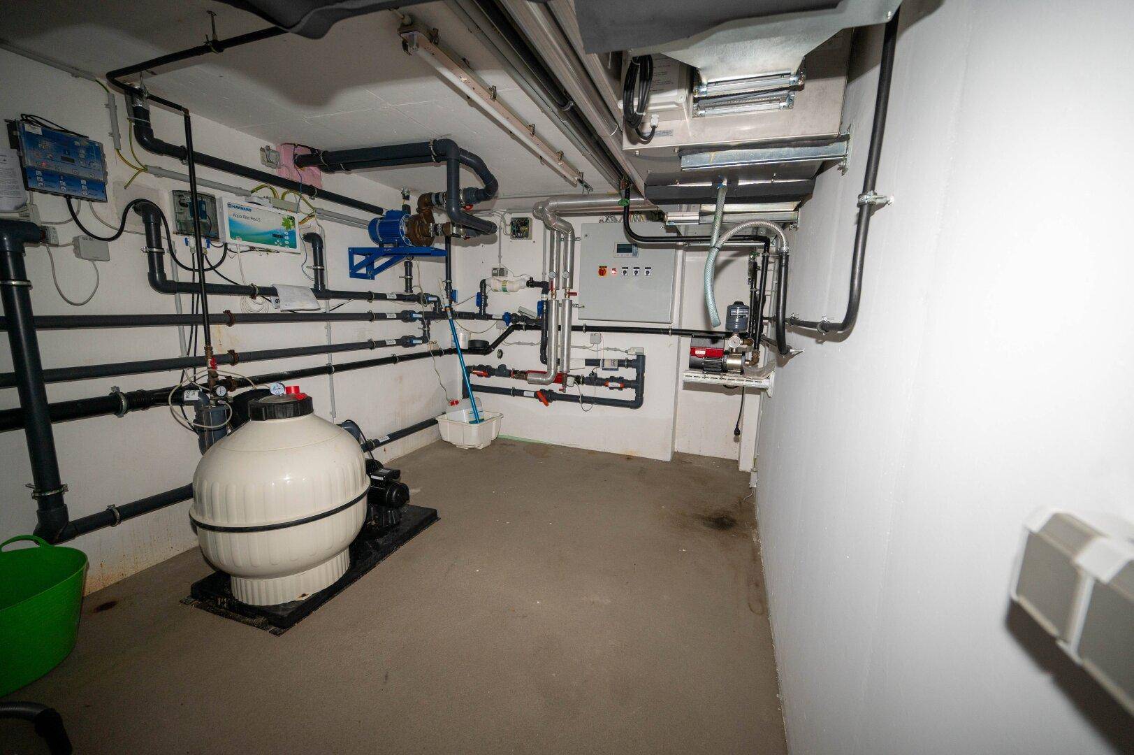 Technikraum für den Pool mit Filteranlage und zahlreichen Leitungen, funktional eingerichtet.