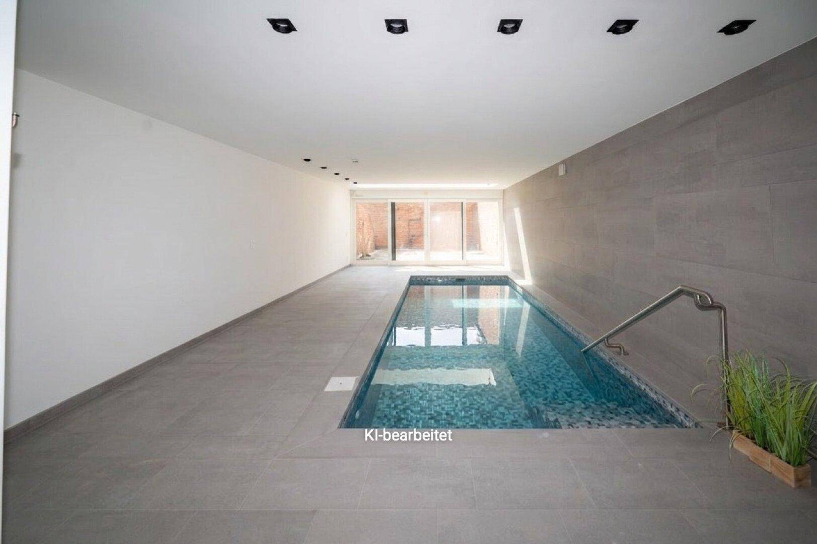 Moderner Innenpool mit Fliesenboden und großen Fenstern, ideal für Entspannung und Sport.