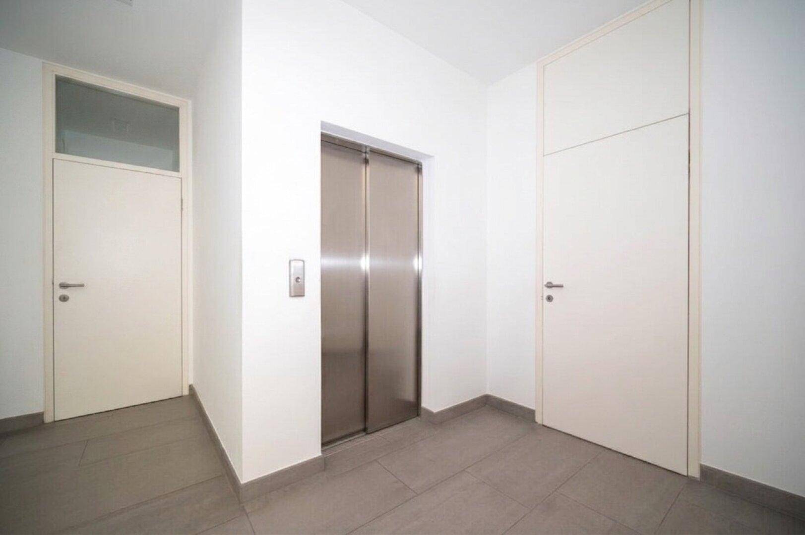Heller Eingangsbereich mit Fliesenboden und einem modernen Aufzug für bequemen Zugang.