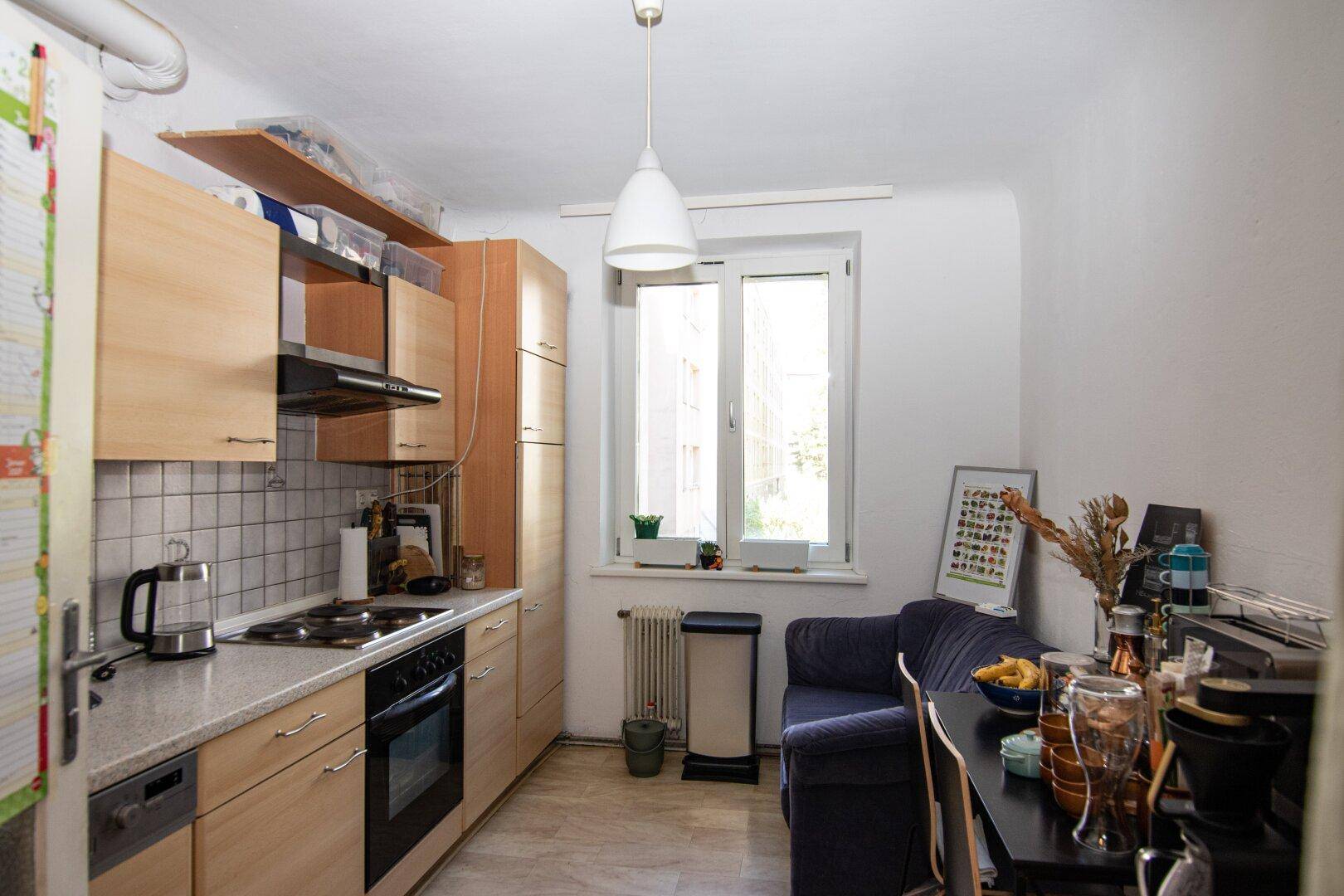 Funktionale Küche mit hellen Holzschränken, Essbereich und einem Fenster für natürliche Belichtung.