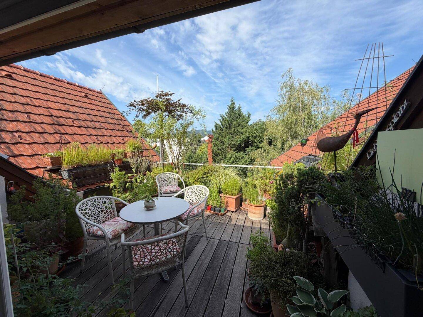 Gemütliche Dachterrasse mit Holzboden, Gartenmöbeln und vielen Pflanzen, bietet einen schönen Ausblick.