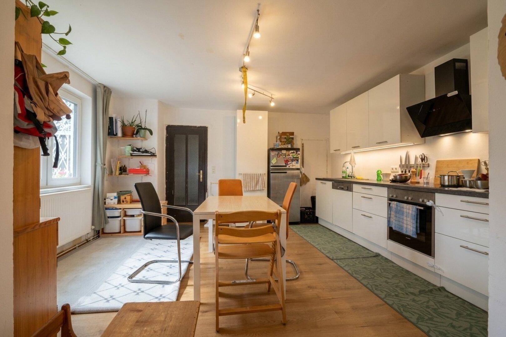 Moderne, offene Küche mit weißen Schränken und Essbereich, verbunden mit dem Wohnraum.