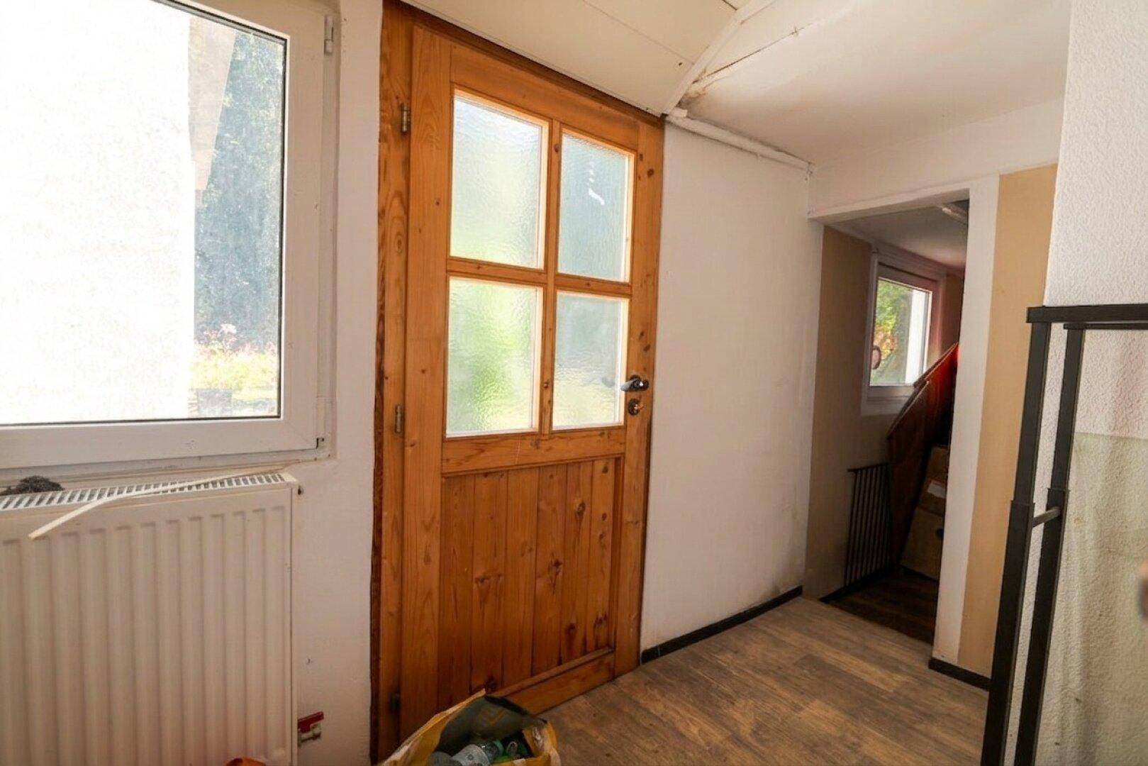 Heller Flur mit rustikaler Holztür und Holzfußboden, führt zu weiteren Räumen.